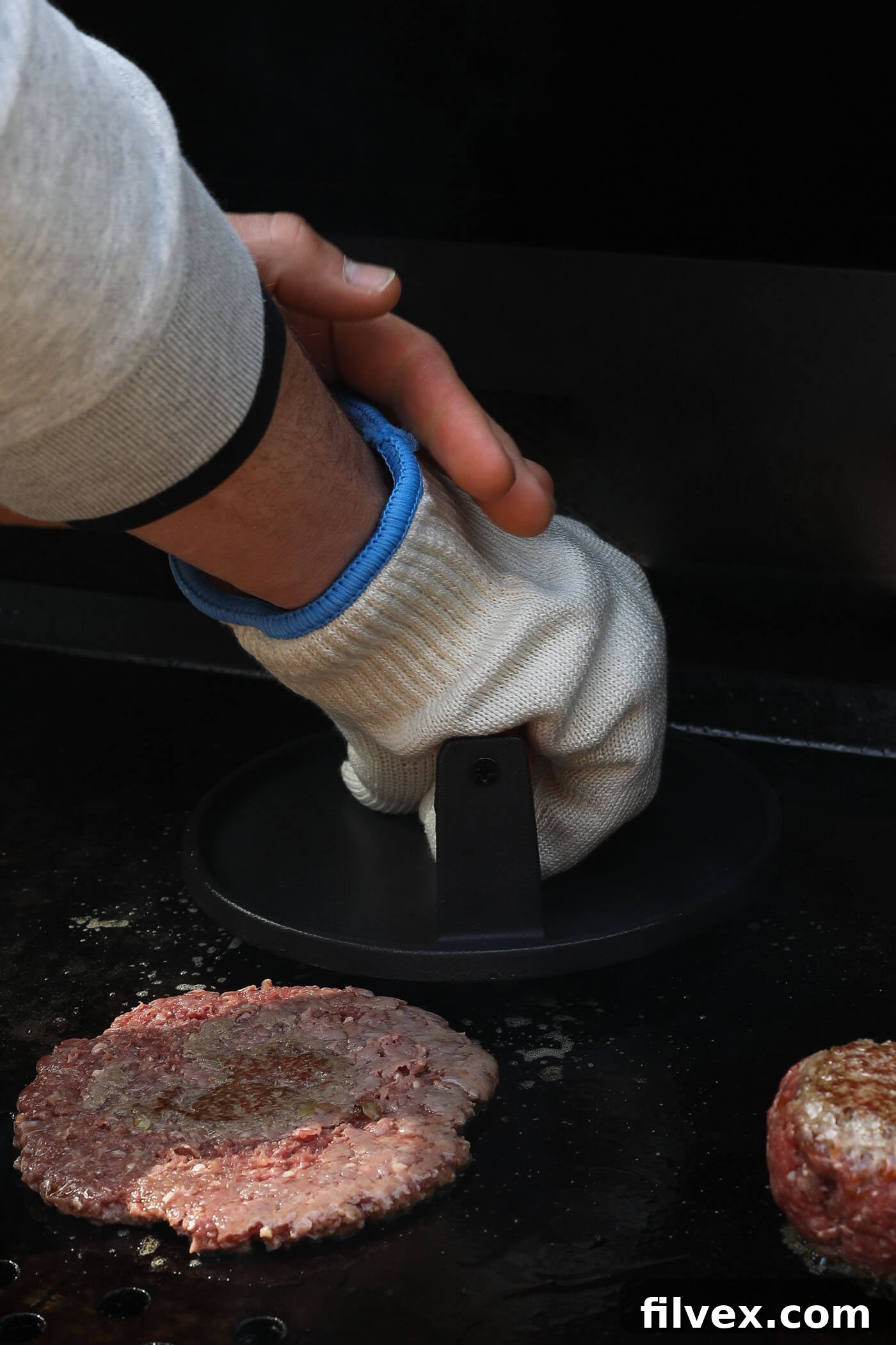 Smashing a burger patty on a griddle with a spatula