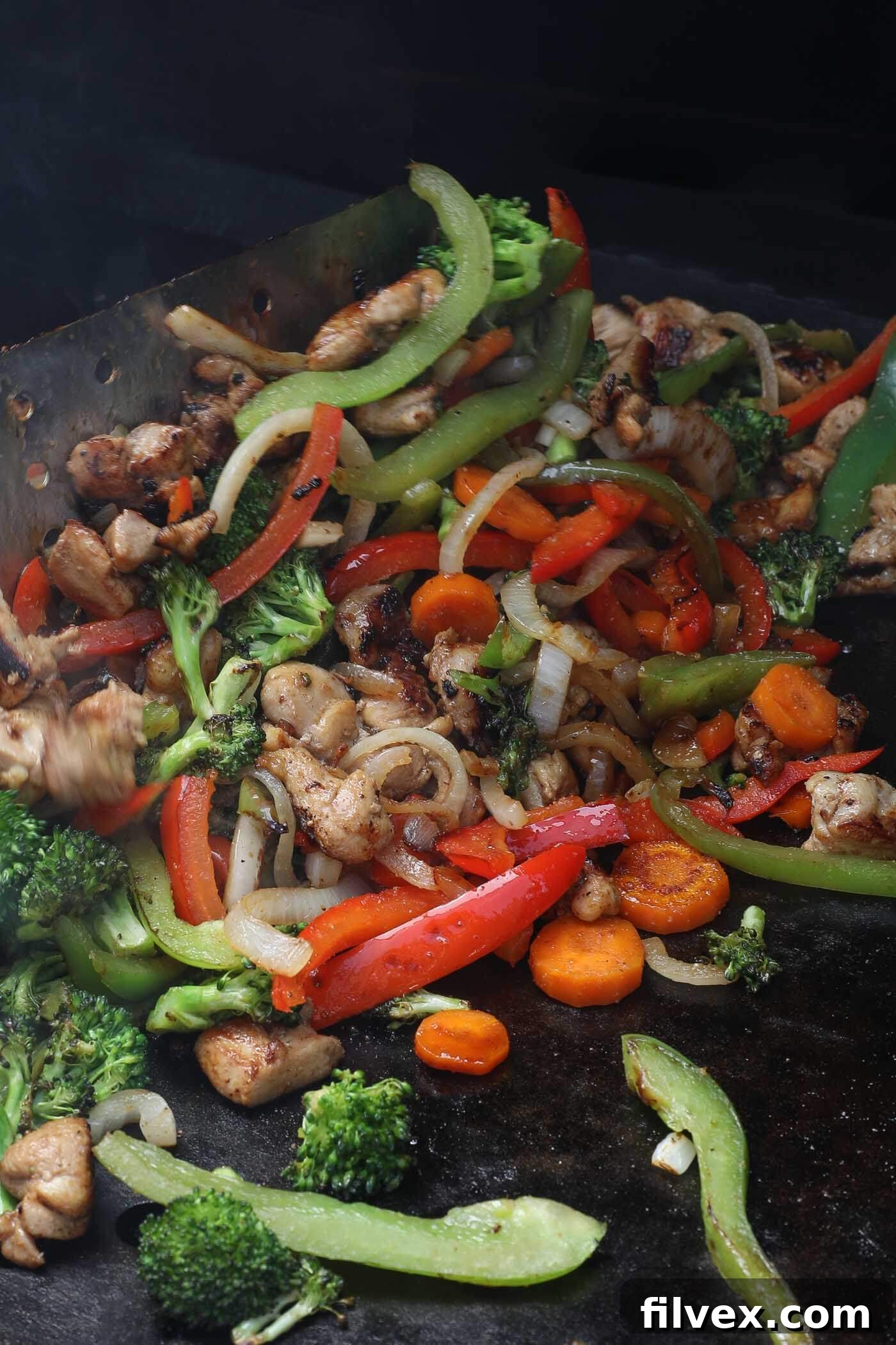 Finished Blackstone Chicken Stir Fry being mixed on the griddle to coat evenly with sauce.