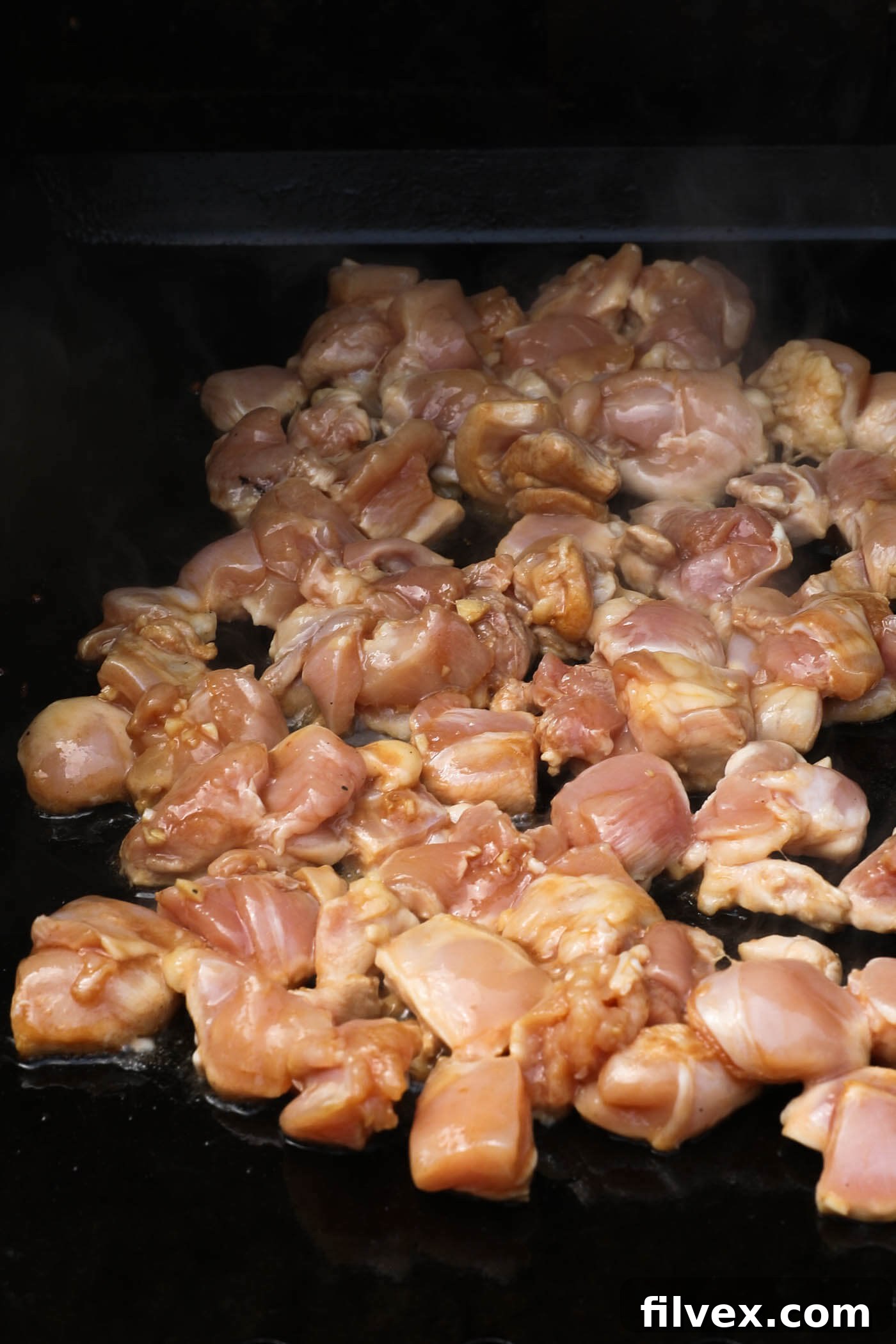 Raw chicken on a griddle top.