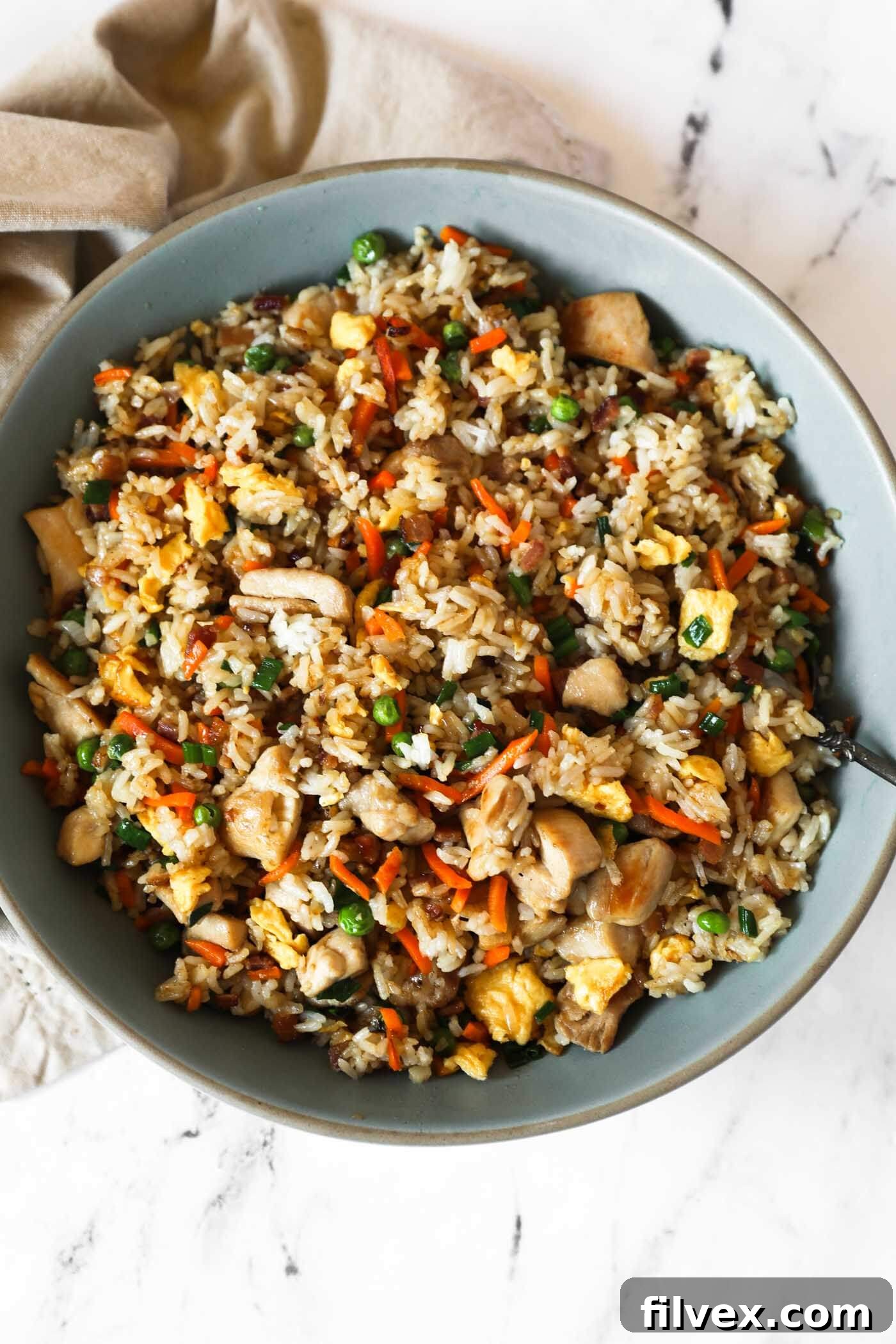 An overhead image of the fried rice in a large serving bowl with a spoon, highlighting the crispy texture.