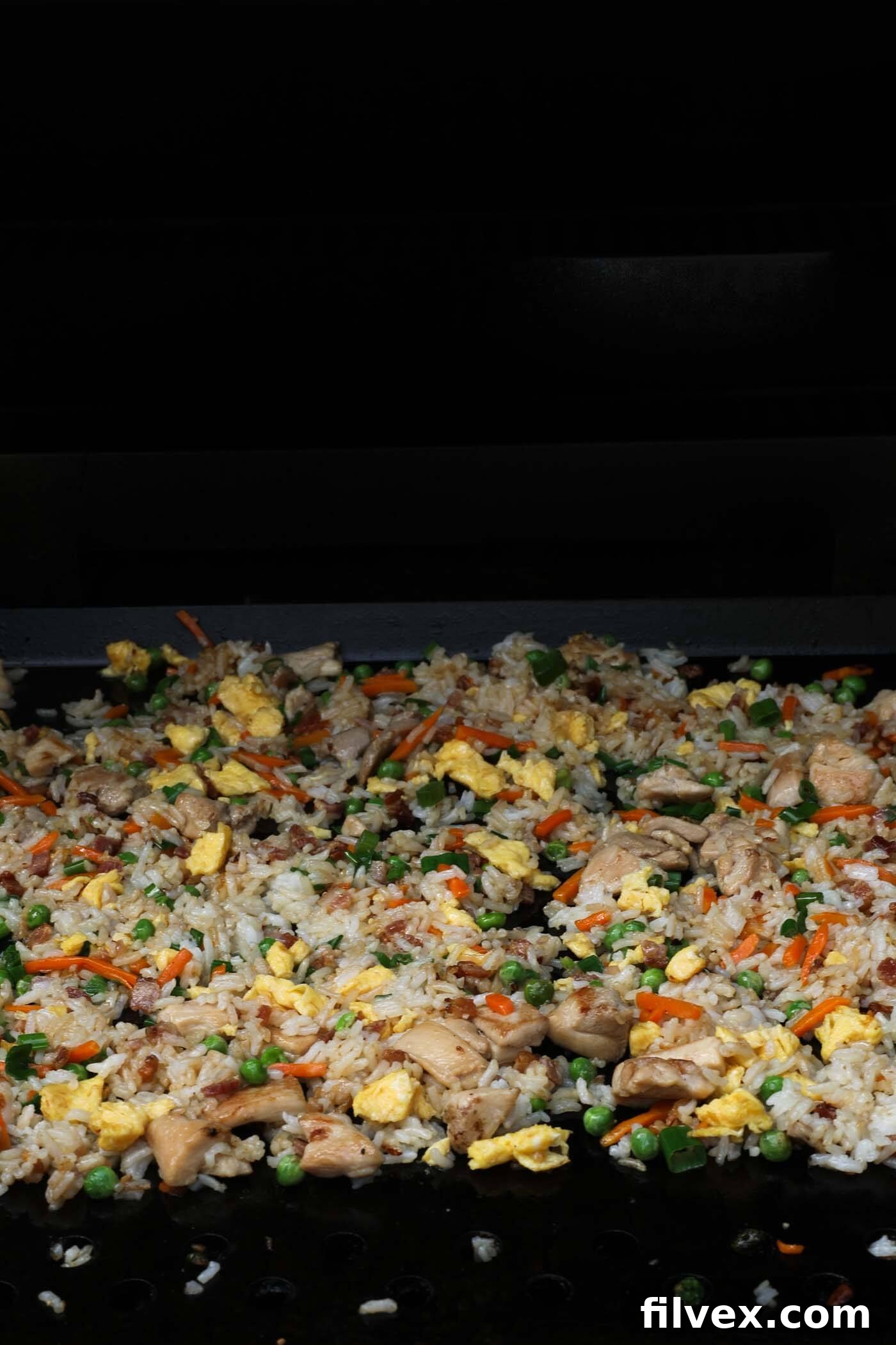 All of the fried rice ingredients cooked and spread out on the Blackstone griddle to get crispy bits formed on the bottom.