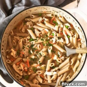 Overhead shot of homemade chicken noodle soup in a large Dutch oven, garnished with fresh parsley.