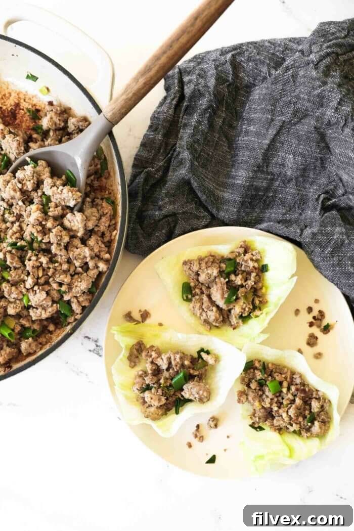 A close-up of a perfectly constructed pork lettuce wrap, showcasing the rich filling and vibrant greens.