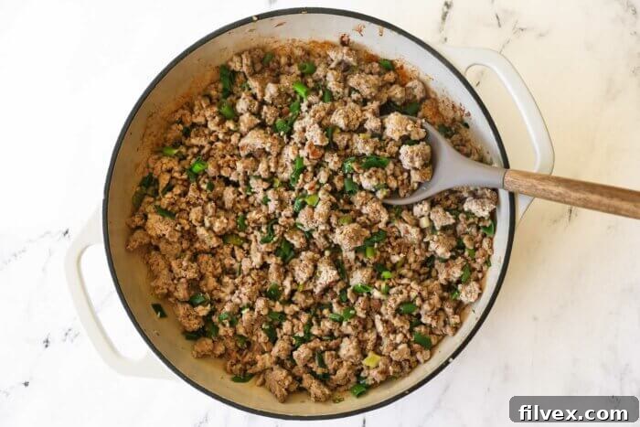 Cooked keto lettuce wrap filling in a skillet with spoon
