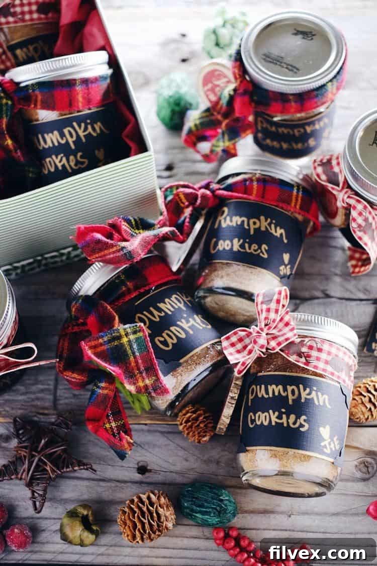 A collection of beautifully prepared DIY Paleo pumpkin cookie mix jars, adorned with plaid ribbon and festive wooden embellishments, ready to be gifted for the holidays. These clean, gluten-free treats are a thoughtful present.