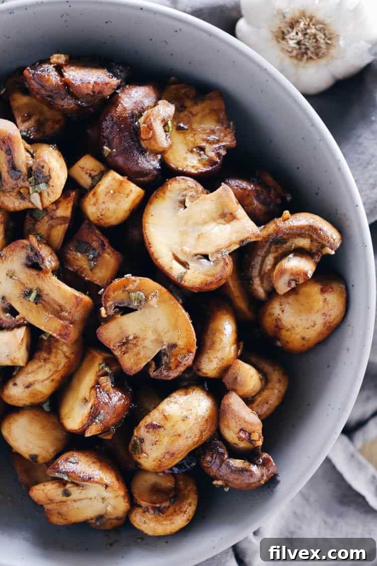 Fresh white button mushrooms and brown cremini mushrooms, some whole, others neatly halved for even cooking.