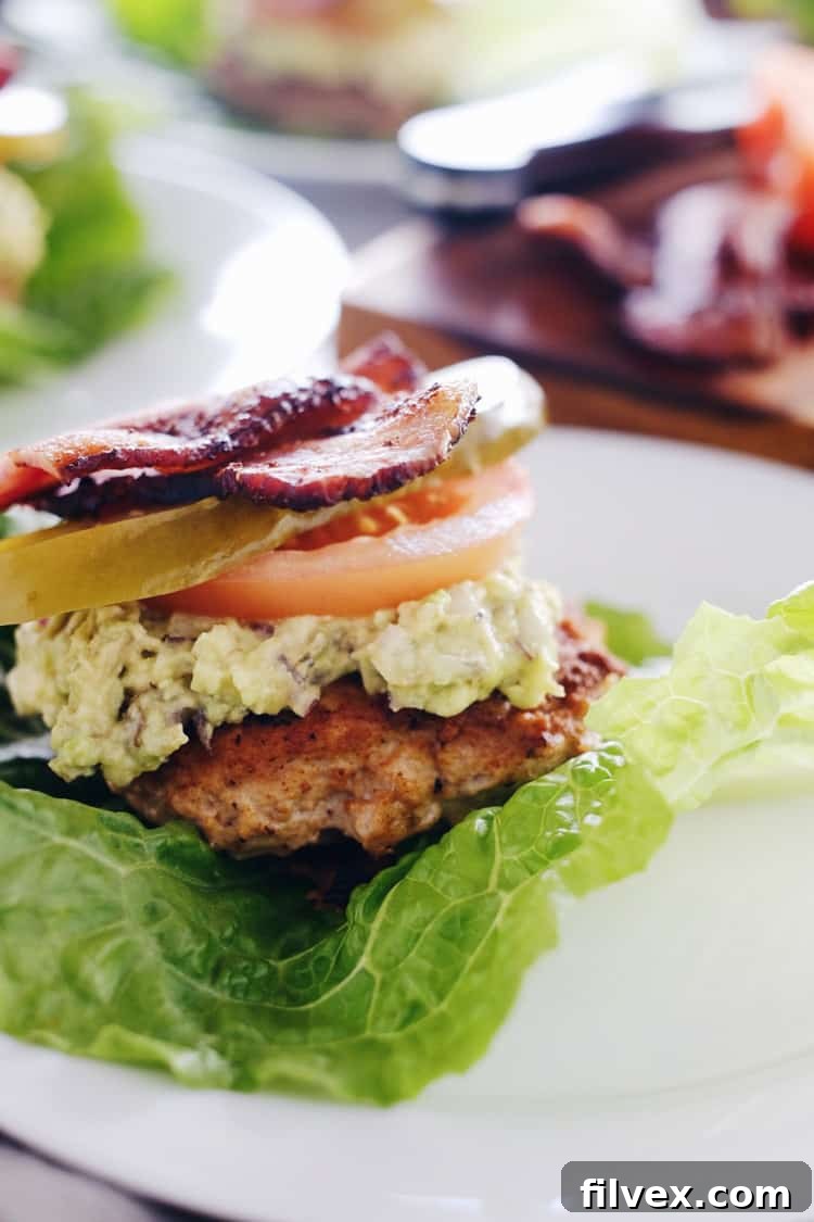 Fresh ingredients for Chipotle Turkey Burgers and guacamole laid out, including ground turkey, chipotle powder, garlic powder, avocados, red onion, bacon, lettuce, and tomato slices.