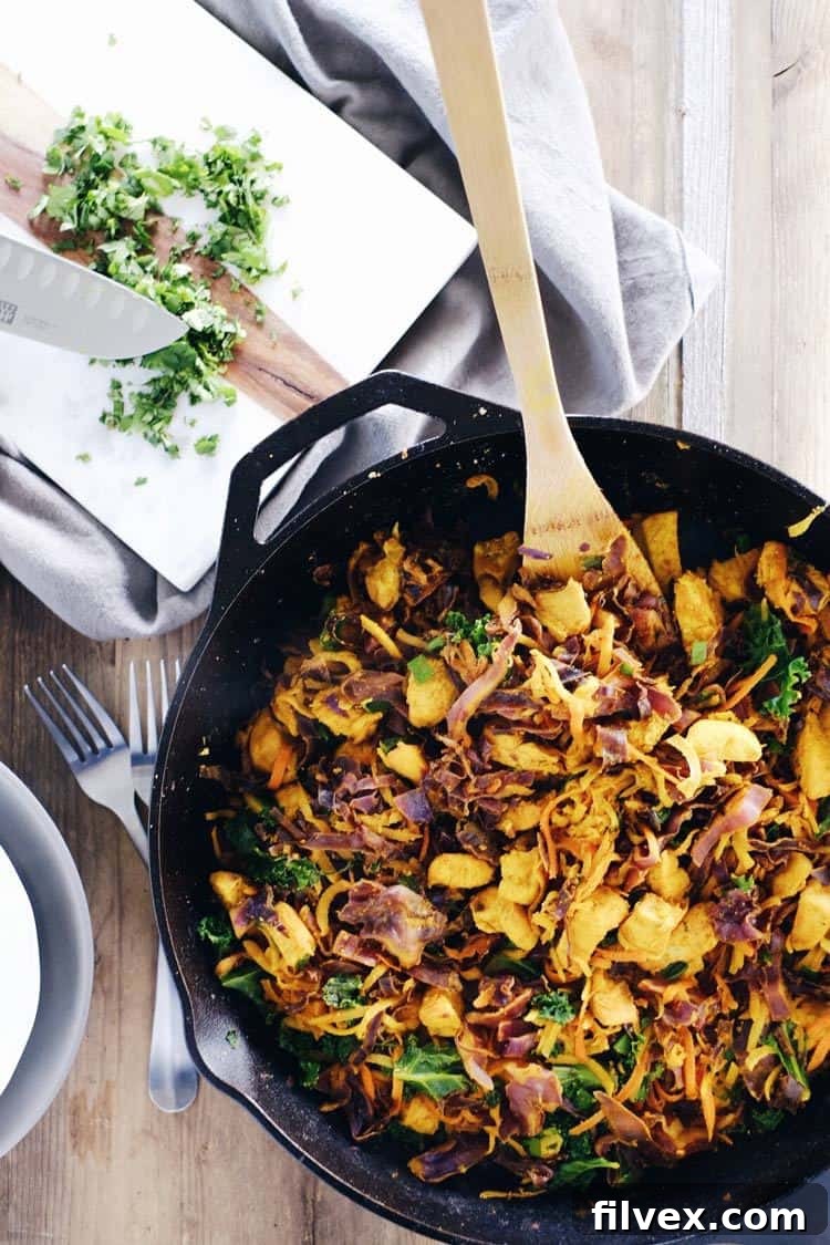 Golden brown chicken and vibrant vegetables cooking in a cast iron skillet.