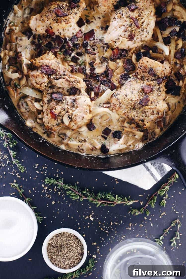 A close-up shot of the creamy low-carb bacon and mushroom chicken skillet, showcasing golden-brown chicken thighs, crisp bacon, and luscious sauce.