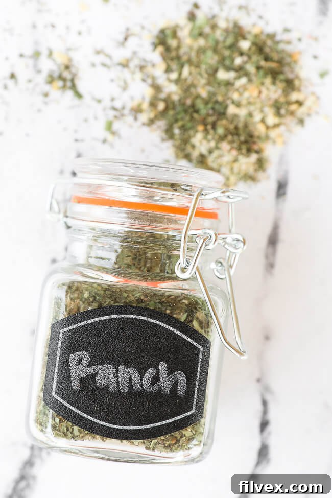 Ranch seasoning mix in a labeled glass jar, lying horizontally on a clean countertop, with some seasoning spilled.