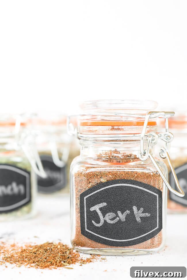 Jerk seasoning blend in a labeled glass jar, with other spice jars softly blurred in the background, creating depth.
