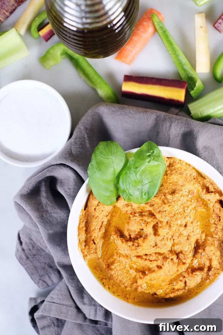 A close-up shot of creamy garlic basil nut hummus, perfect for Paleo, Whole30, and Keto diets. Garnished with fresh basil leaves and a drizzle of olive oil, ready for dipping.