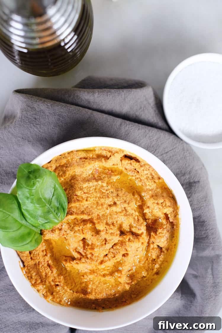 A serving platter with a generous portion of garlic basil nut hummus and a variety of fresh dipping vegetables, ideal for entertaining at any gathering.