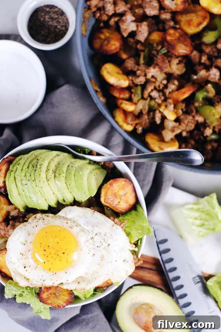 A vibrant Pork and Plantain Bowl, featuring tender ground pork, sweet baked ripe plantains, fresh avocado slices, and green leafy vegetables. This Paleo, Whole30, Gluten-Free, and Dairy-Free dish offers big flavor with few ingredients, ideal for healthy eating.
