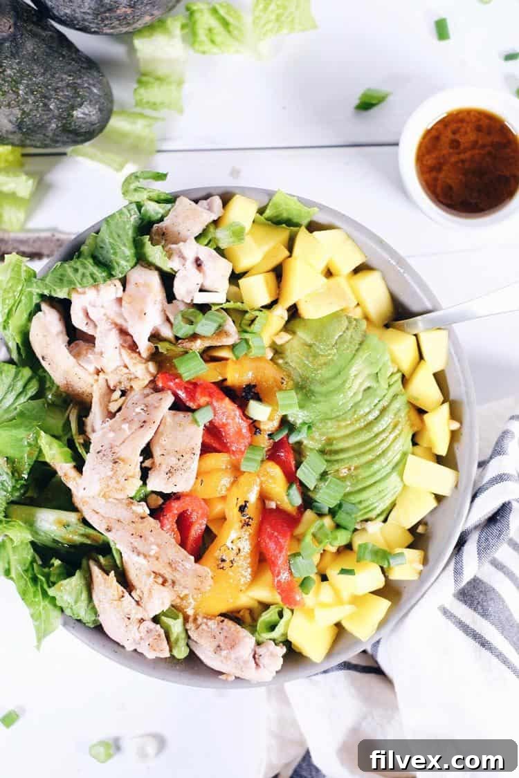 Vibrant chili lime chicken salad with fresh mango, avocado, and roasted peppers, served in a bowl.